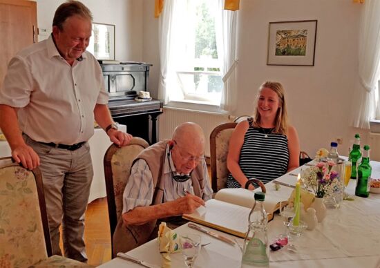Herr Schabacker aus Lomnitz trägt sich an seinem 100. Geburtstag in das "Goldene Buch" der Gemeinde Wachau ein.